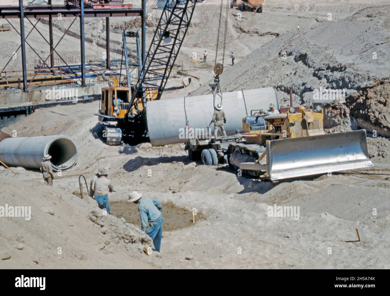 Construction work on the Wellton-Mohawk canal, near Yuma, Arizona, USA in the early 1950s. Here the workers use a crane to lay the concrete pipes that will lift water at one of the pumping stations along the canal. The Wellton-Mohawk Irrigation and Drainage District is located in south-west Arizona, east of Yuma, built between 1949 and 1957. It allows the irrigation in the Lower Gila valley with water from the Colorado river via the Gila Canal to the Wellton-Mohawk Canal, where it is pumped around 160 feet to the headwaters – a vintage 1950s photograph. Stock Photo