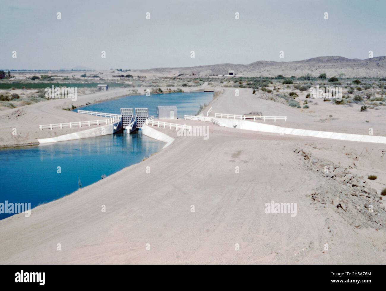 The Wellton-Mohawk canal, near Yuma, Arizona, USA in the early 1950s. Here a canal ‘turnout’ is now in water. The Wellton-Mohawk Irrigation and Drainage District is located in south-west Arizona, east of Yuma, built between 1949 and 1957. It allows the irrigation in the Lower Gila valley with water from the Colorado river via the Gila Canal to the Wellton-Mohawk Canal, where it is pumped around 160 feet to the headwaters – a vintage 1950s photograph. Stock Photo