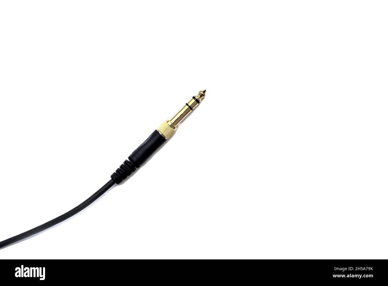 Stereo audio headphone jack with cable on white background. Gold jack plug for connecting audio devices and musical instruments. Stock Photo