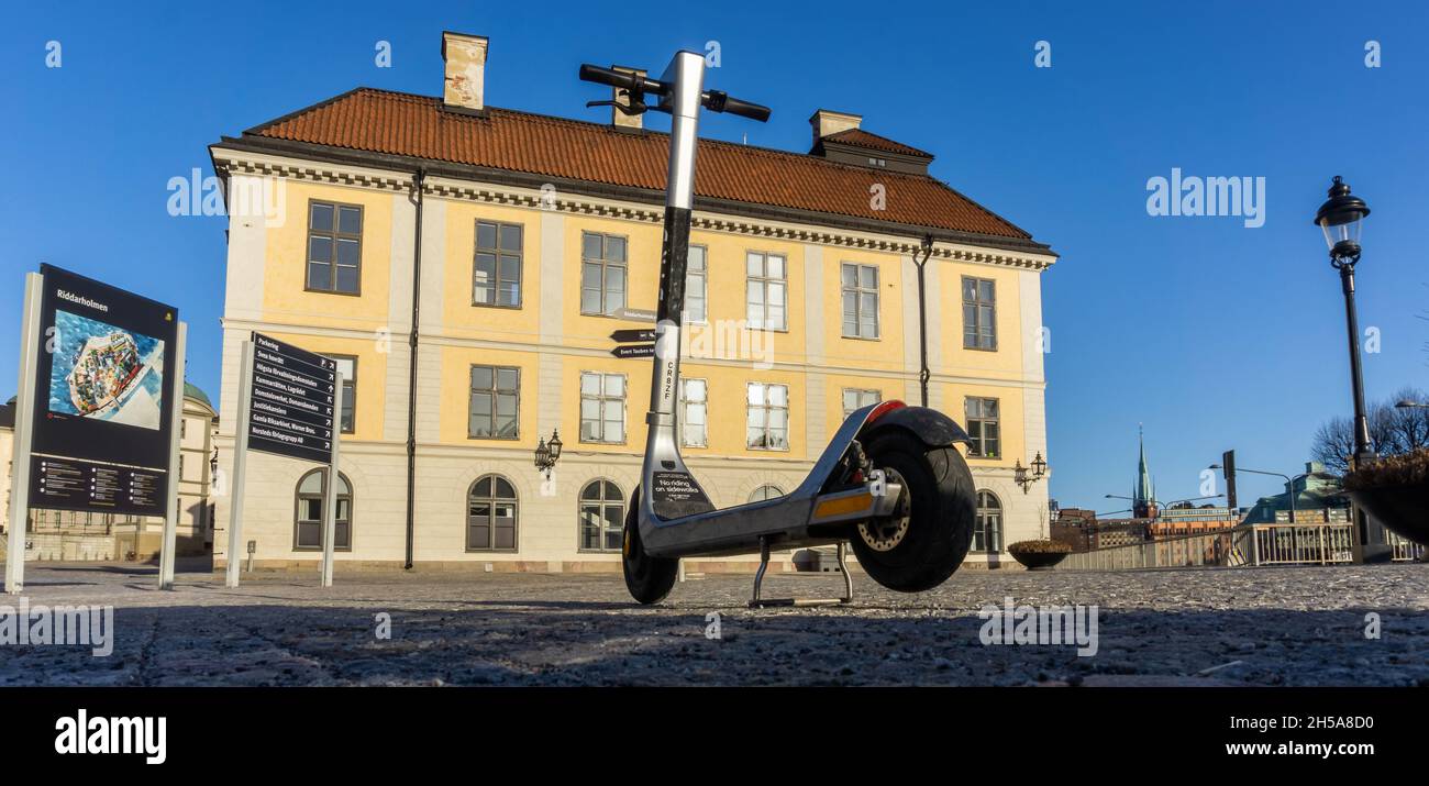 Stockholm, Sweden - April 3, 2021: Silver rent-a-scooter left near old buildings on one of small islands in the center of Stockholm Stock Photo