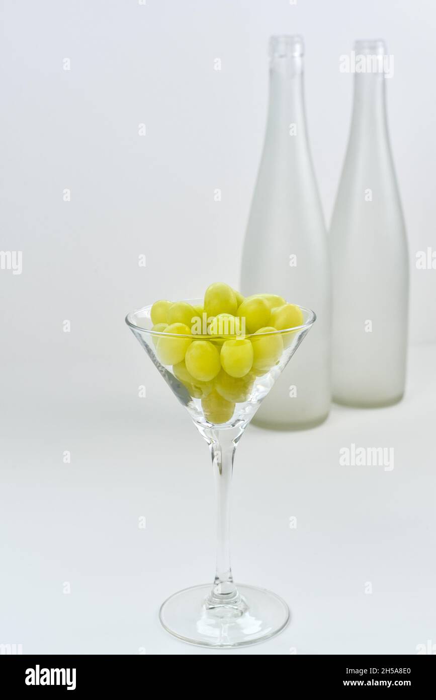Glass with grapes on the background of a blurry empty wine bottles. Wine production and wine making theme Stock Photo