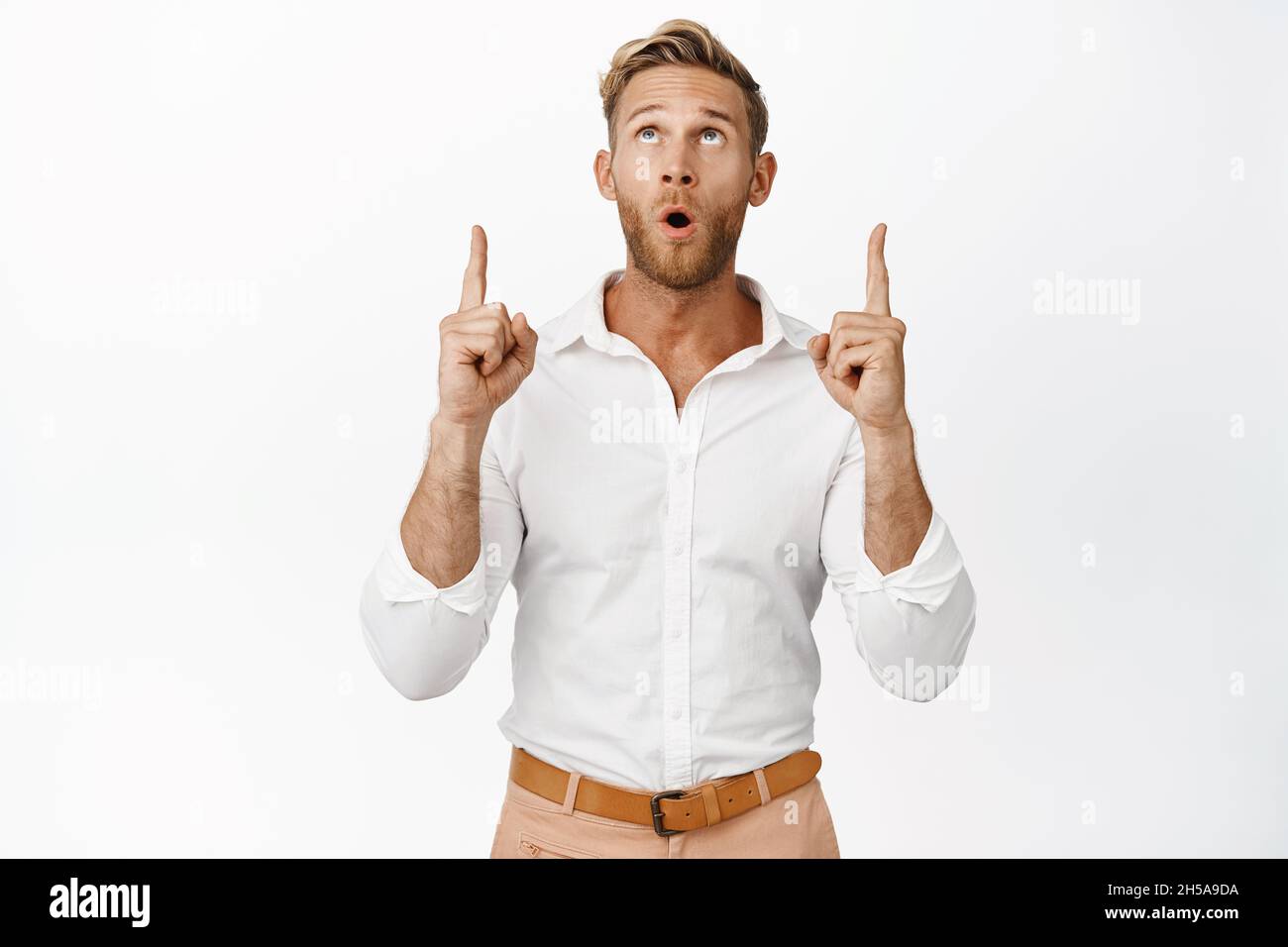 Portrait of handsome man pointing and looking up with wow face ...