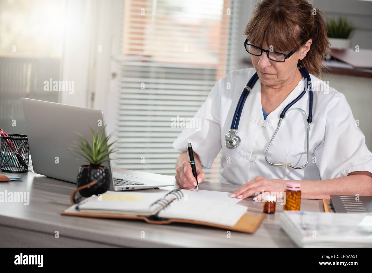 Female doctor writing prescription in medical office Stock Photo - Alamy