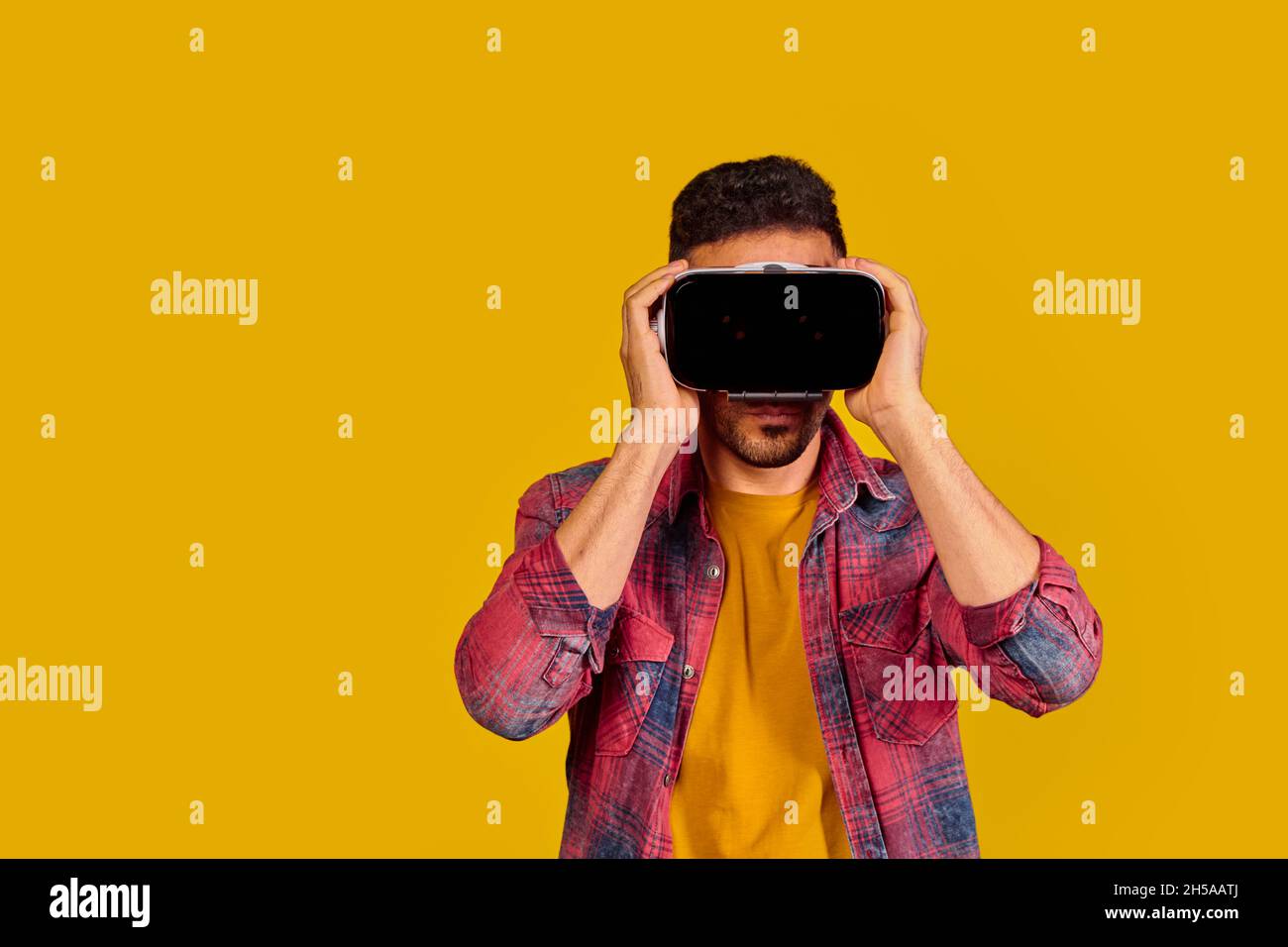 Man having fun with virtual reality glasses. Studio shot, yellow background Stock Photo