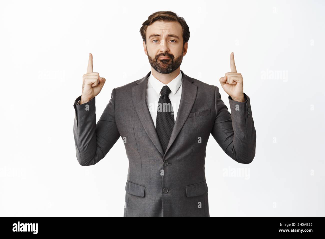 Sad and disappointed businessman in suit pointing fingers up, pulling