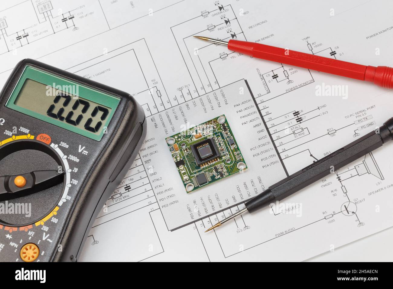 The module with an image sensor and a multimeter lies in the circuit diagram. The concept of debugging, repairing electronic equipment Stock Photo