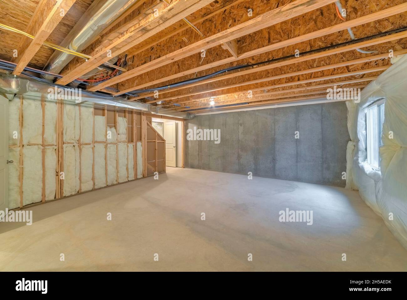 Unfinished basement with a plastic vapor barrier on the wall Stock