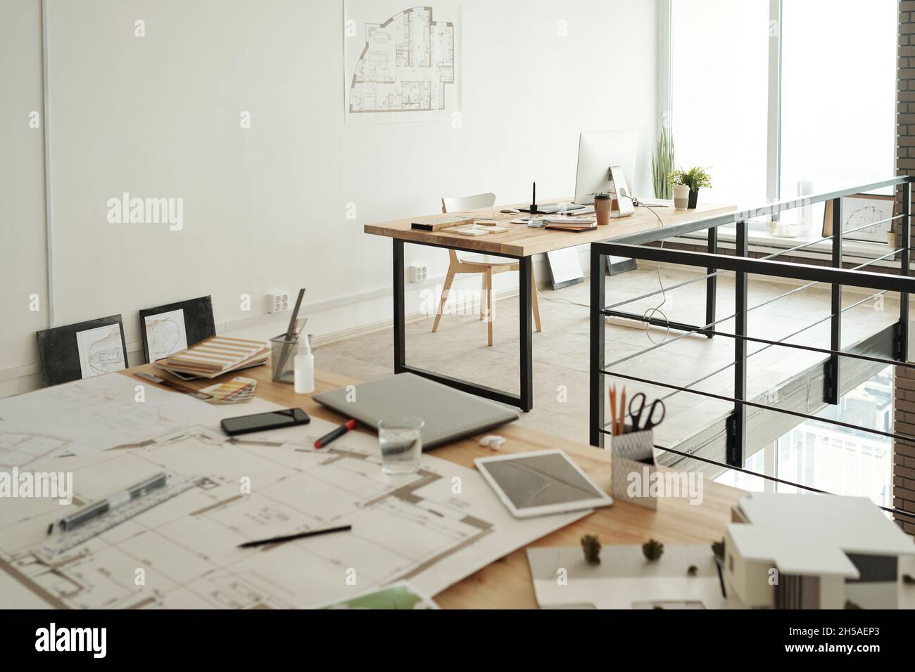 https://c8.alamy.com/comp/2H5AEP3/two-workplaces-consisting-on-tables-with-sketches-blueprints-gadgets-samples-and-other-supplies-in-large-contemporary-openspace-office-2H5AEP3.jpg