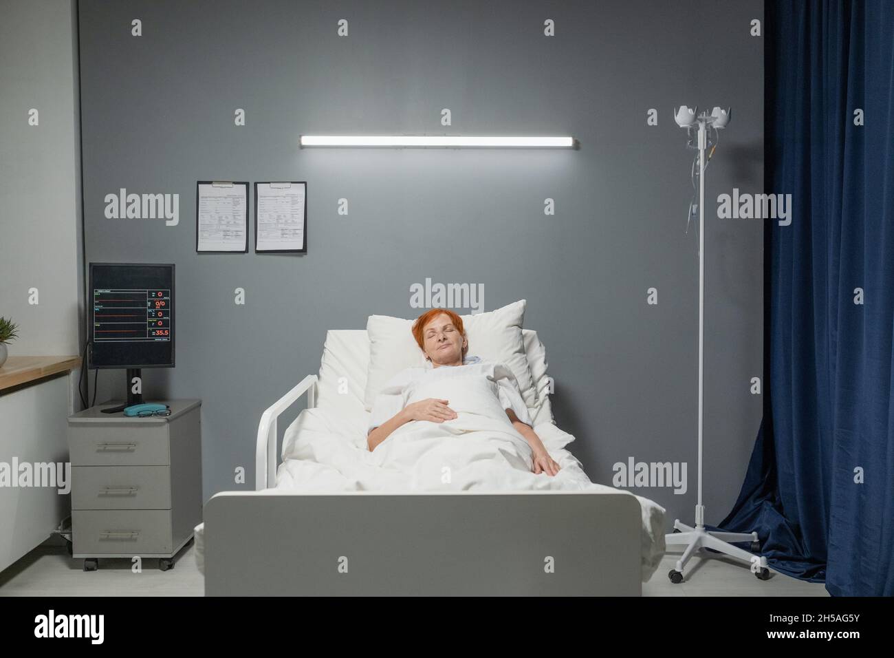 Sick senior woman sleeping in bed at hospital ward during covid epidemic Stock Photo