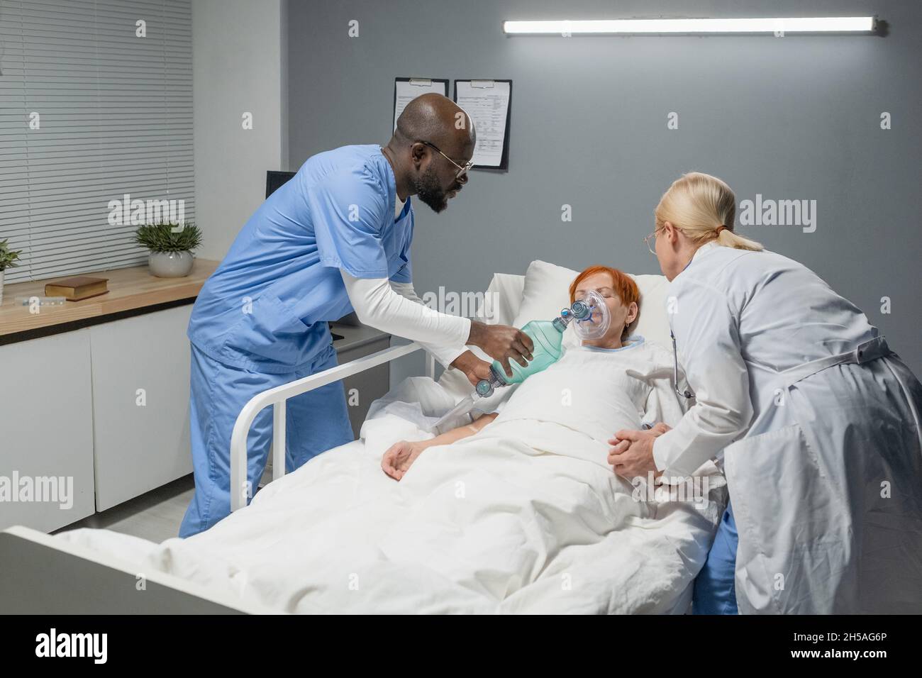 Senior woman breathing hard and doctors giving her an oxygen mask in