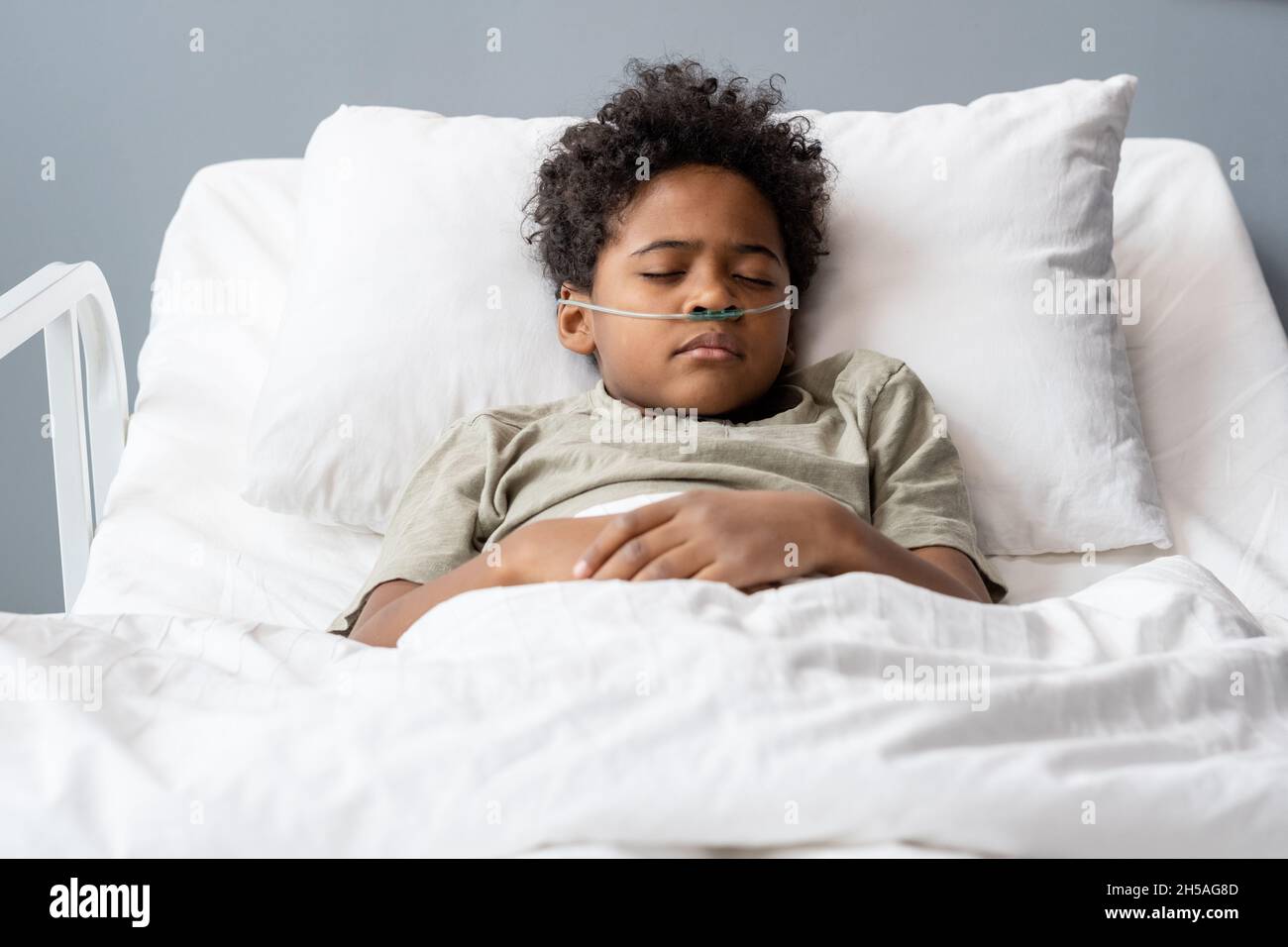 Hard sick boy with tubes in his nose sleeping in bed at hospital Stock