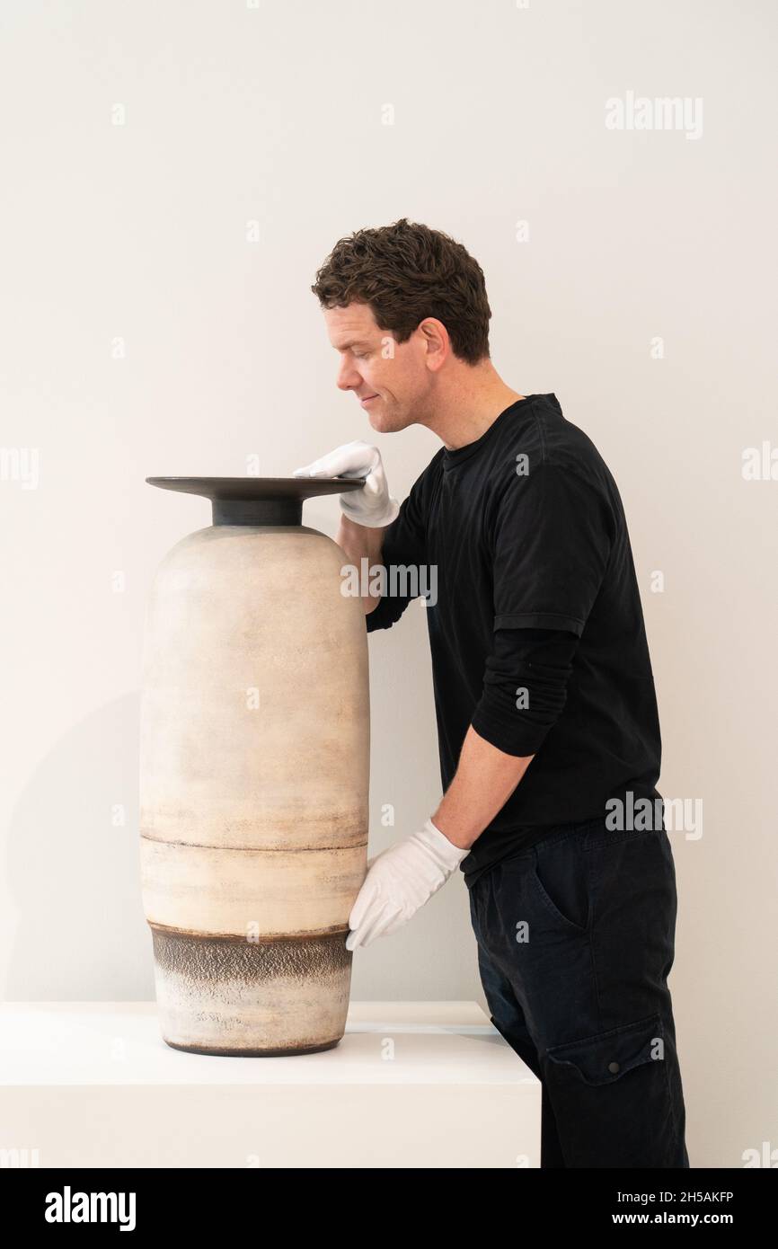An art handler at Phillips auction house handles a Monumental 'Writhlington School' pot, by Hans Coper, valued at £80,000 to £120,000, part of a rare ceramics collection of the late Dr. John P Driscoll, expected to sell collectively for 2 million (sterling) on 10 November at the London auction house. Picture date: Monday November 8, 2021. Stock Photo