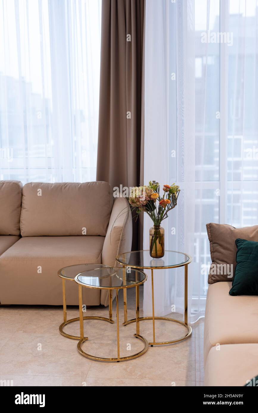 Glass round bedside table with gold with a vase of flowers in a modern