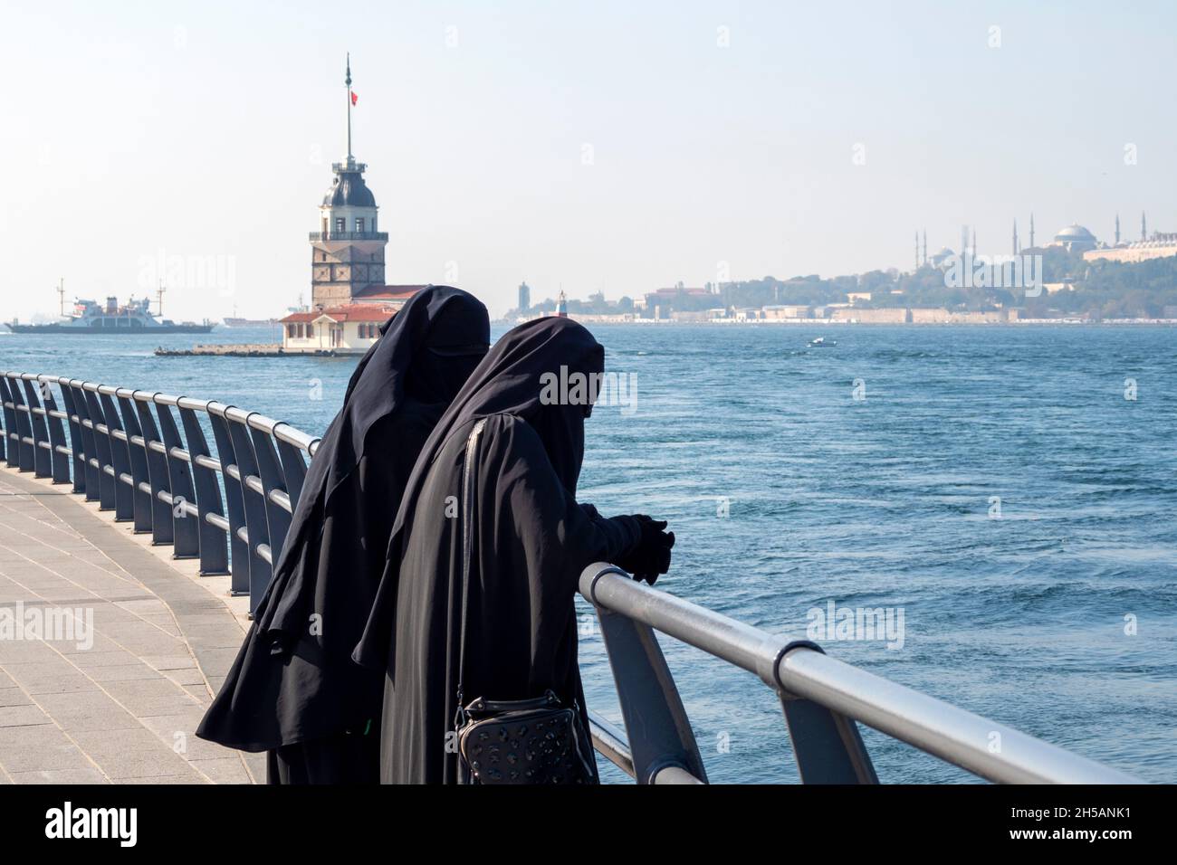 Two woman dressed in traditional muslim dresses black hijab, burqa and walking at the embankment in Istanbul, Turkey Stock Photo