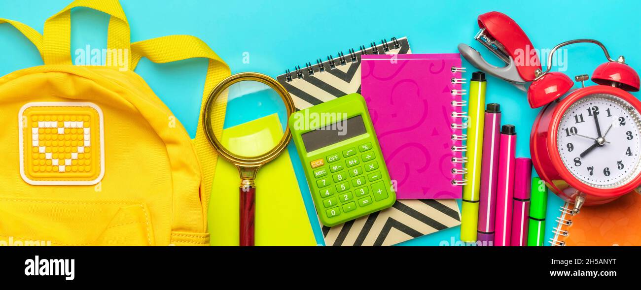 Frame from school and office supplies Paper clips, scissors, pens, felt-tip pens, sharpener, calculator, stapler isolated on blue background Flat lay Stock Photo