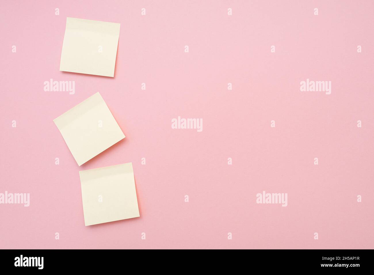 Three blank memo stickers on pink surface. Top view, space for text. Stock Photo