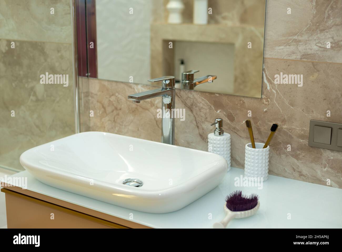 Modern bathroom in beige tones with marble tiles and white sink