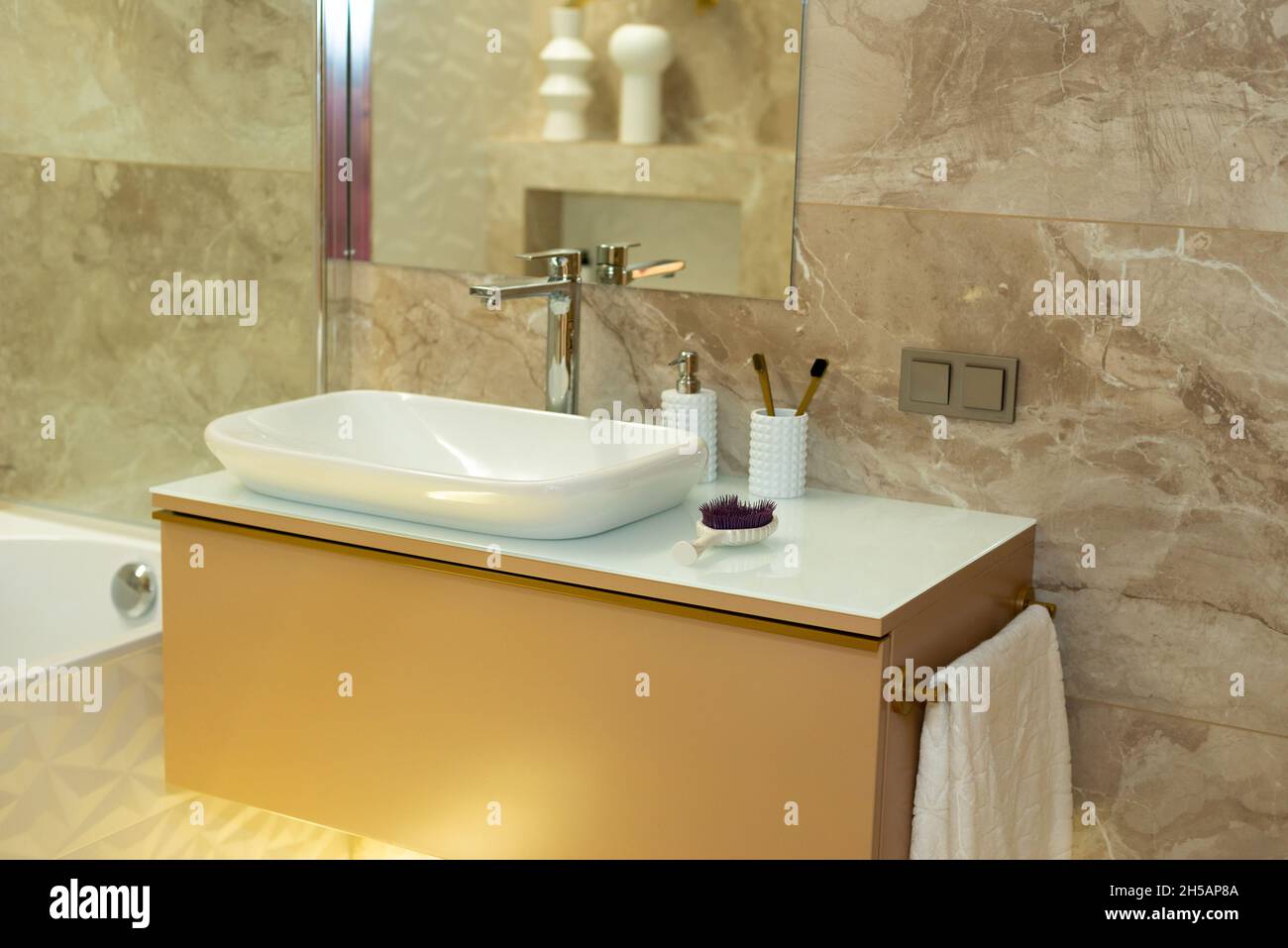 Modern bathroom in beige tones with marble tiles and white sink