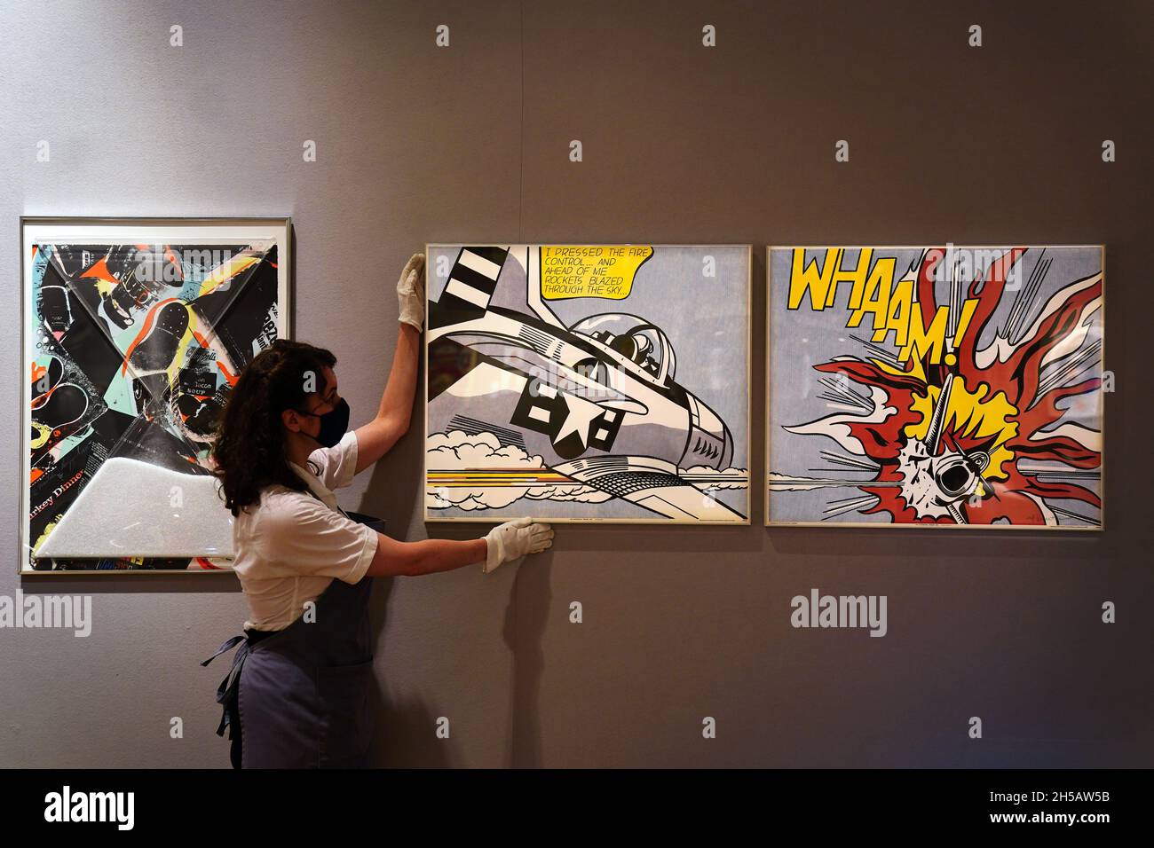 A Bonhams gallery assistant adjusts Whaam! 1967 by Roy Lichtenstein, estimated to fetch £8,000 to £12,000, as part of Bonhams' forthcoming Pop x Culture Sale at their London auction house. Picture date: Monday November 8, 2021. Stock Photo