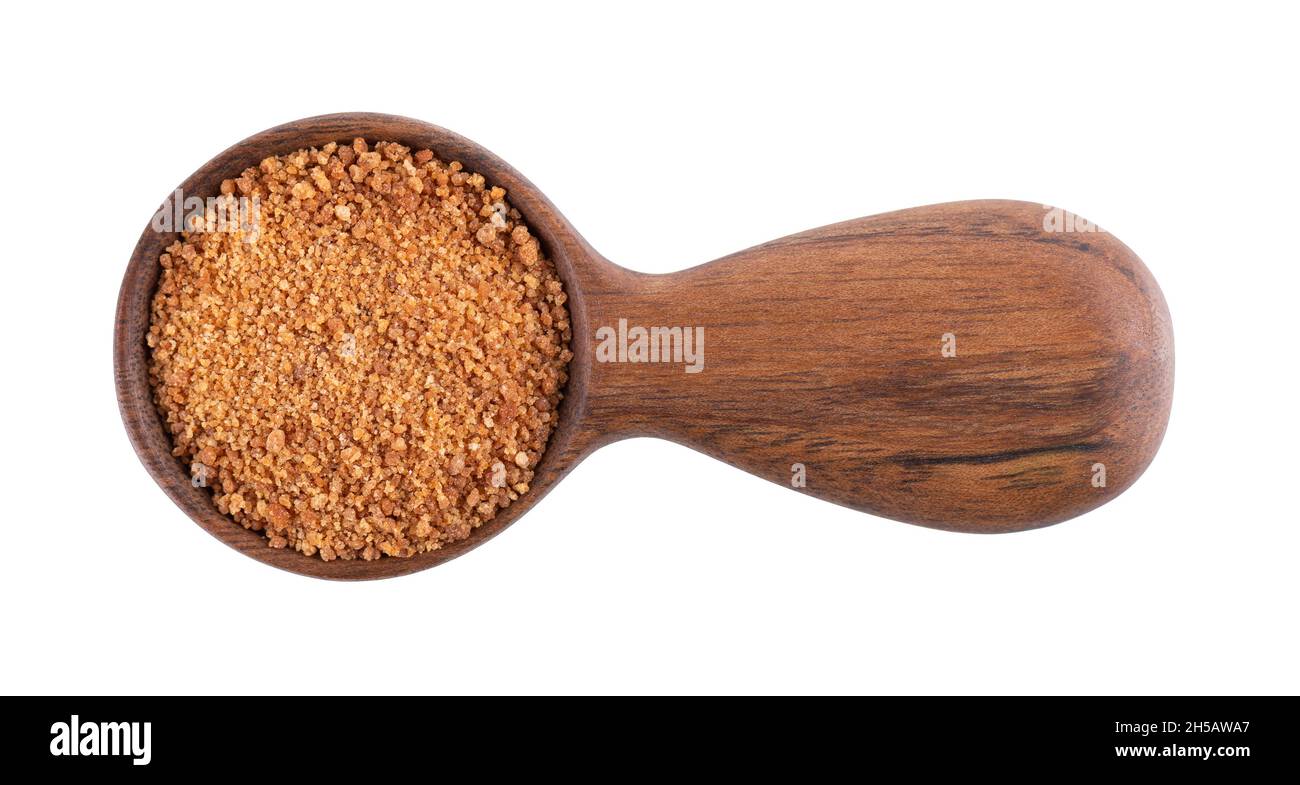 Coconut sugar isolated on white background. Brown unrefined coconut palm sugar in wooden spoon. Top view. Stock Photo