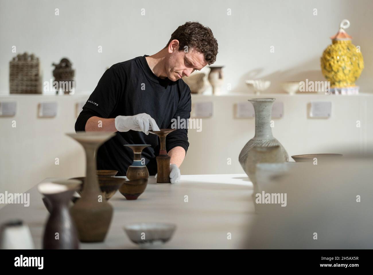 London, UK.  8 November 2021. A technician examines 'Rare vase with flaring lip', by Lucie Rie, circa 1980, (Est. £20,000-30,000) at the preview of a collection of museum quality studio contemporary ceramics of the late Dr John P Driscoll. The collection of over 160 works is expected to sell for £2m on 10 November at Phillips in Berkeley Square in an auction entitled The Art of Fire.  Credit: Stephen Chung / Alamy Live News Stock Photo