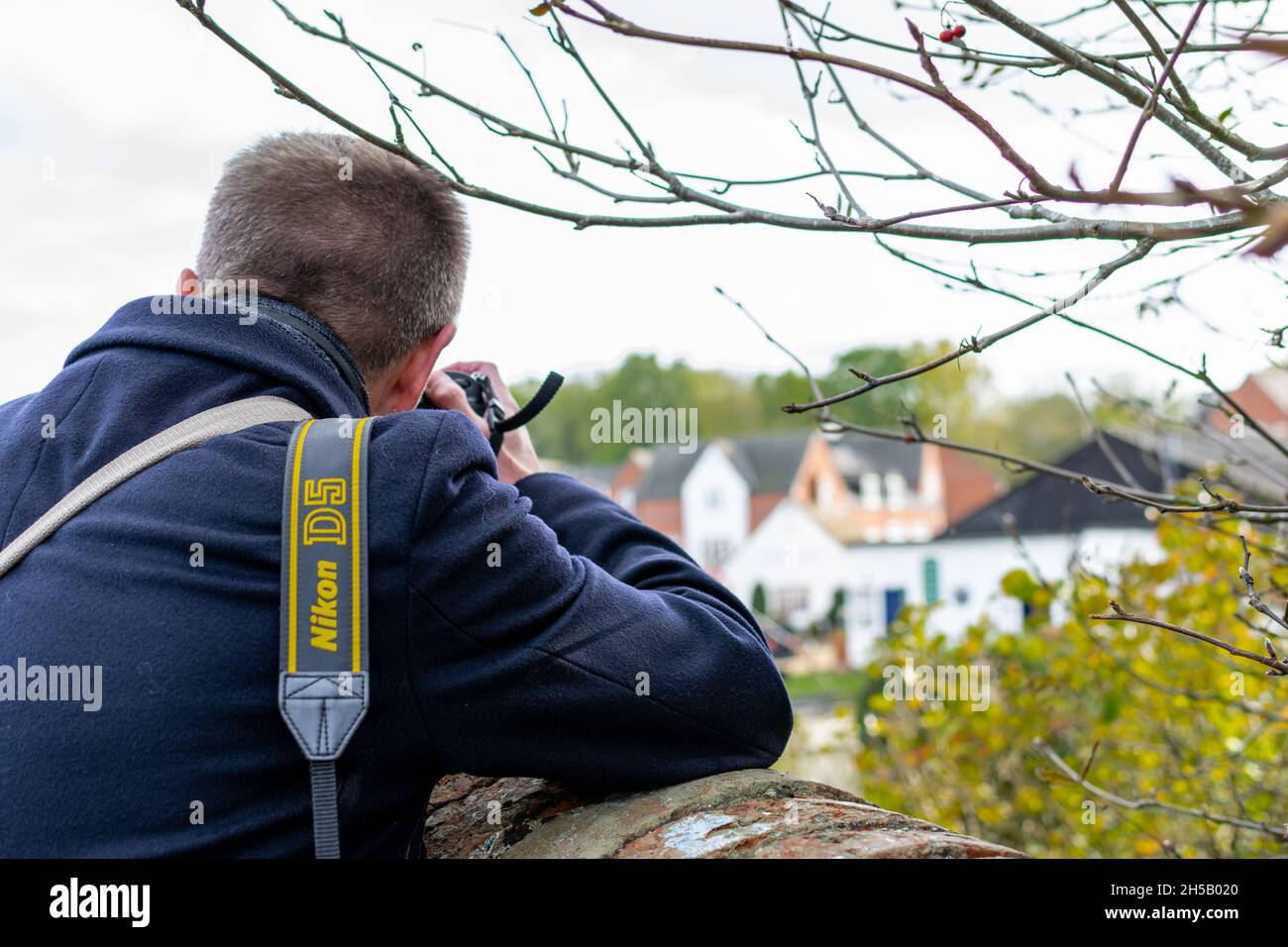 Photojournalist taking a photo using a wall to steady himself Stock Photo