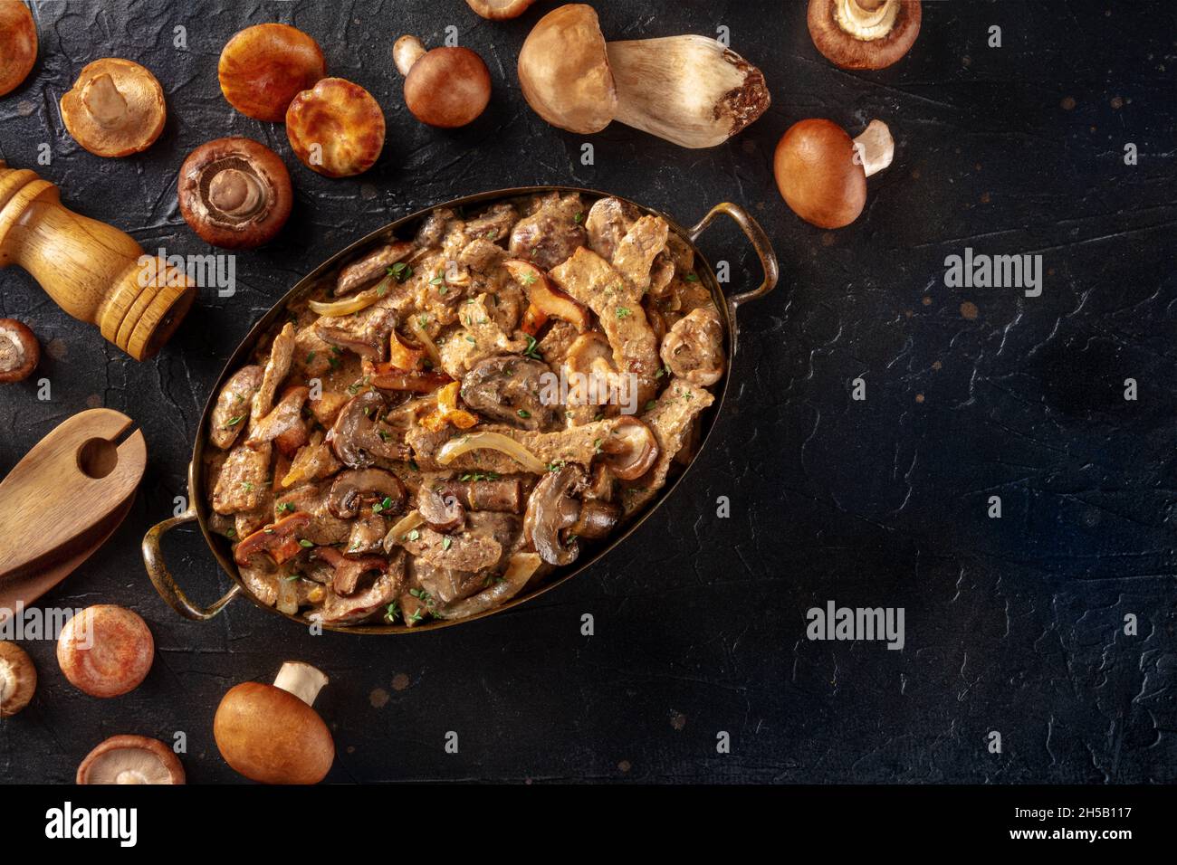 Beef stroganoff, mushroom and meat ragout with cream sauce, traditional Russian dish, shot from the top on a black slate background Stock Photo