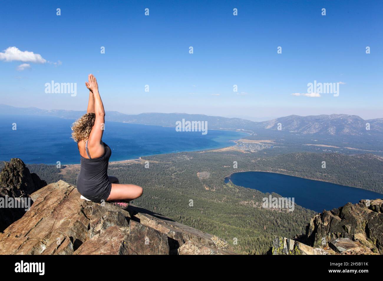 Woman meditates on a rock on mount Tallac overlooking lake Tahoe California Stock Photo