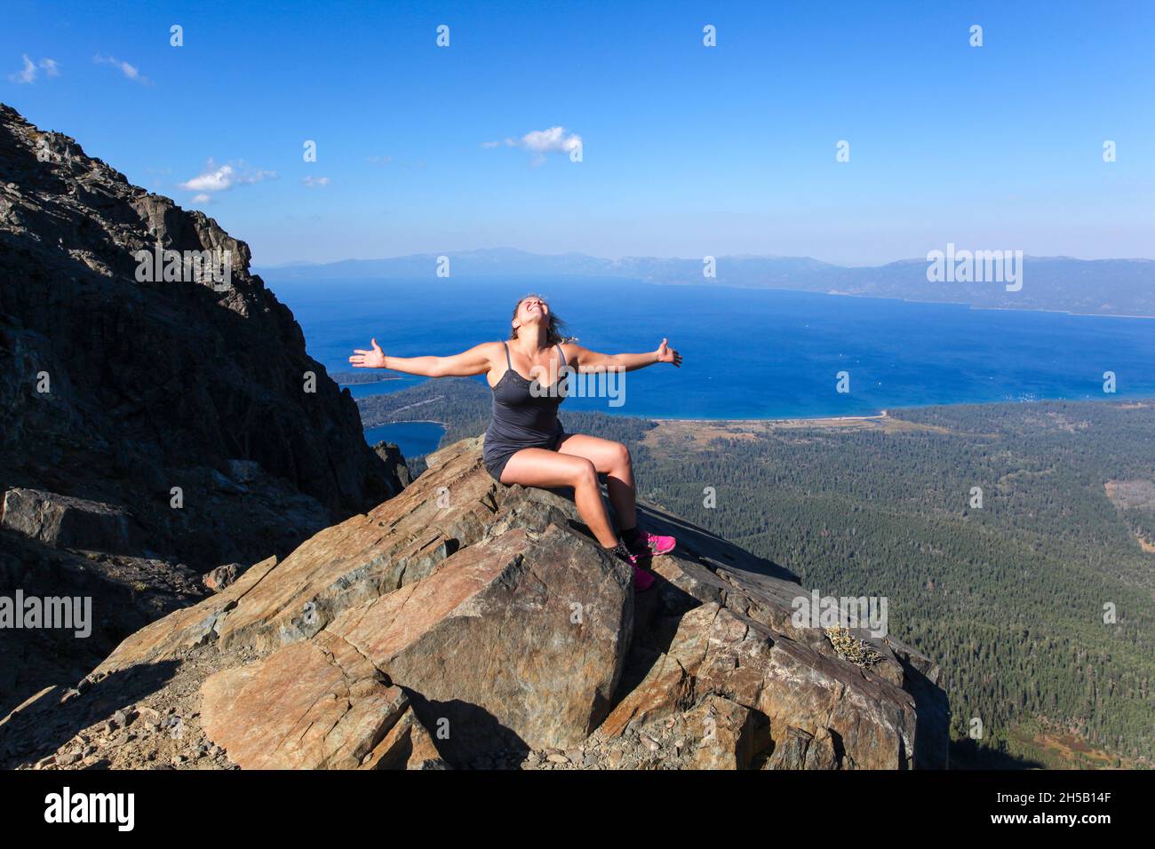 Woman meditates on a rock overlooking lake Tahoe California Stock Photo