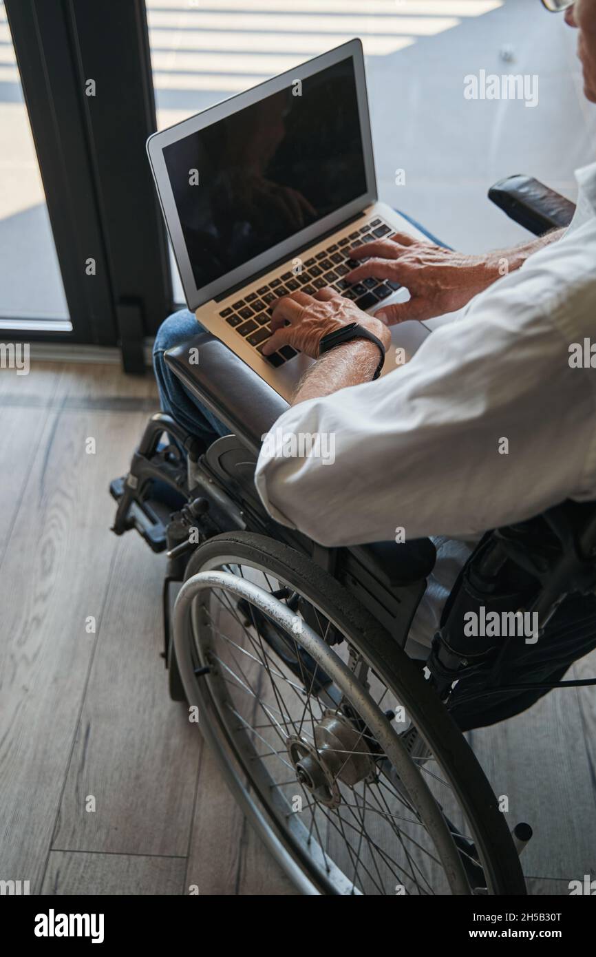 Person with disability using laptop from wheelchair Stock Photo