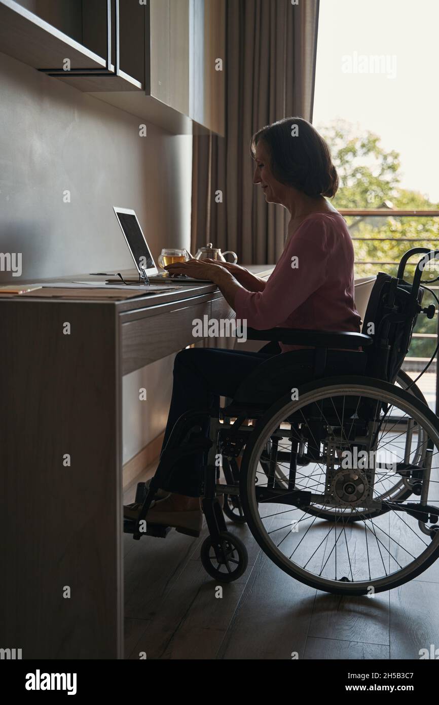 Female with disability working with laptop at desk Stock Photo