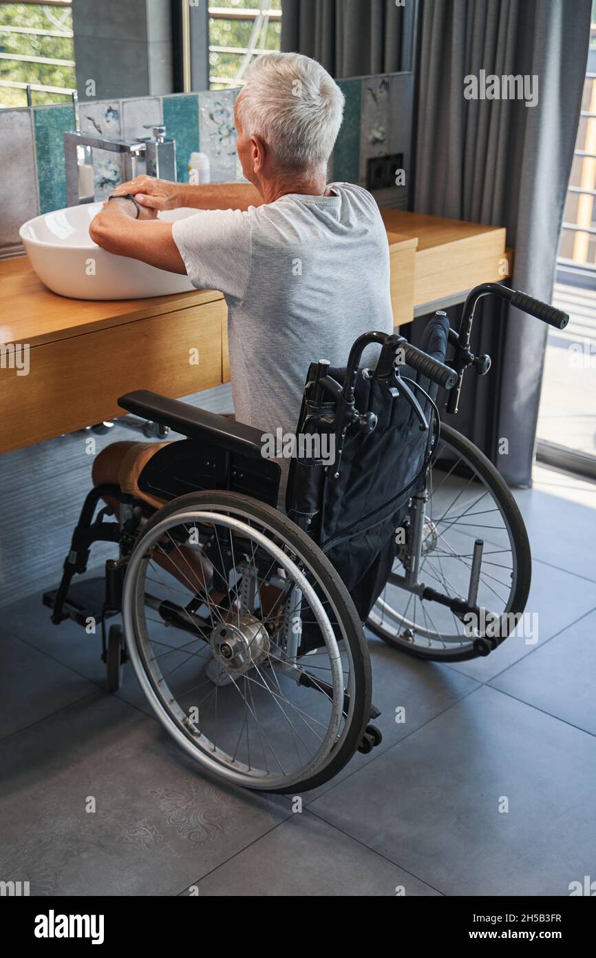 Aging male who lives with disability washing his hands Stock Photo