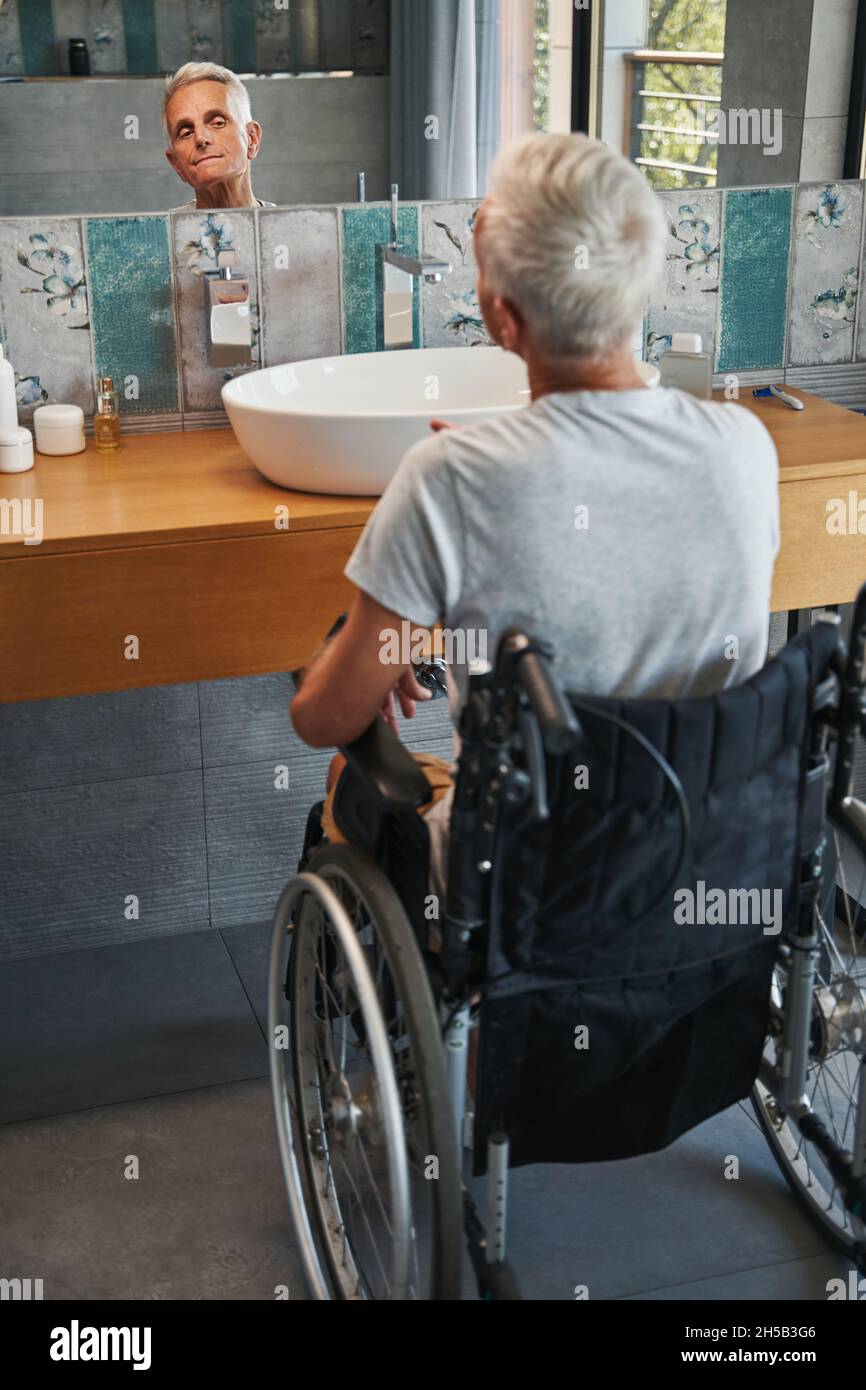 Pensioner with disability checking his face in mirror Stock Photo