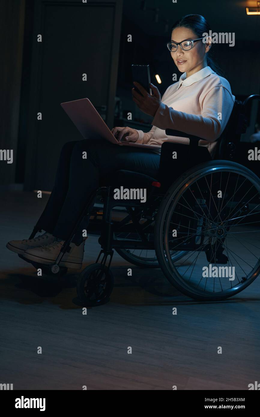 Female with disability working online at home at night Stock Photo - Alamy