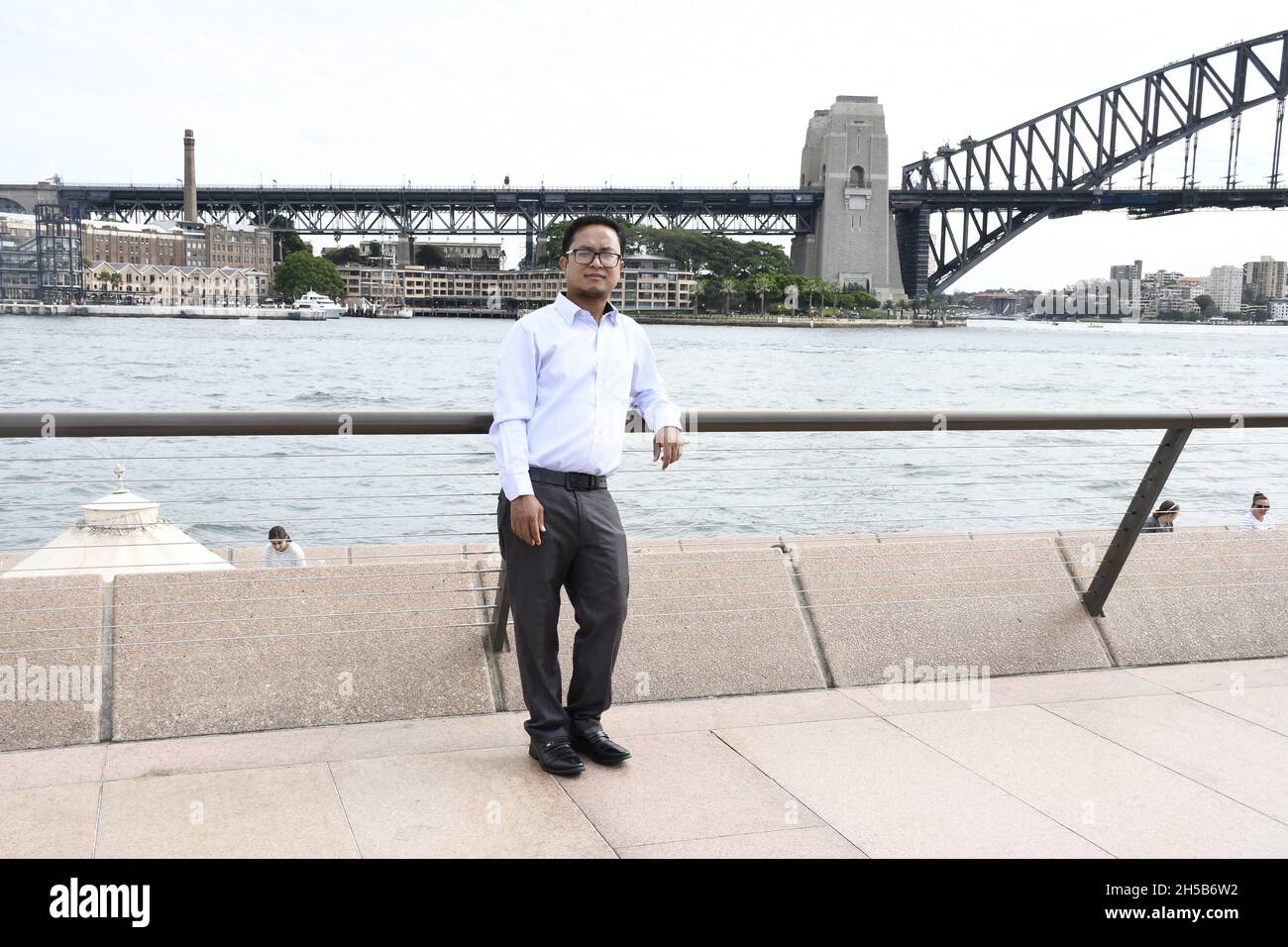 South Asian Man posing, leaning on a abridge in formal dress on a sunny ...