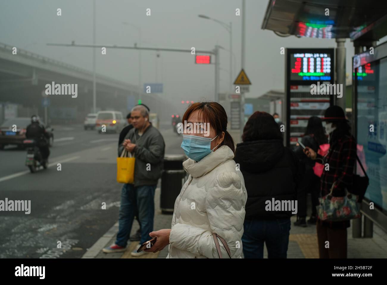 People wear masks to protect against both covid-19 and heavy smog at a bus station in Beijing, China. 06-Nov-2021 Stock Photo