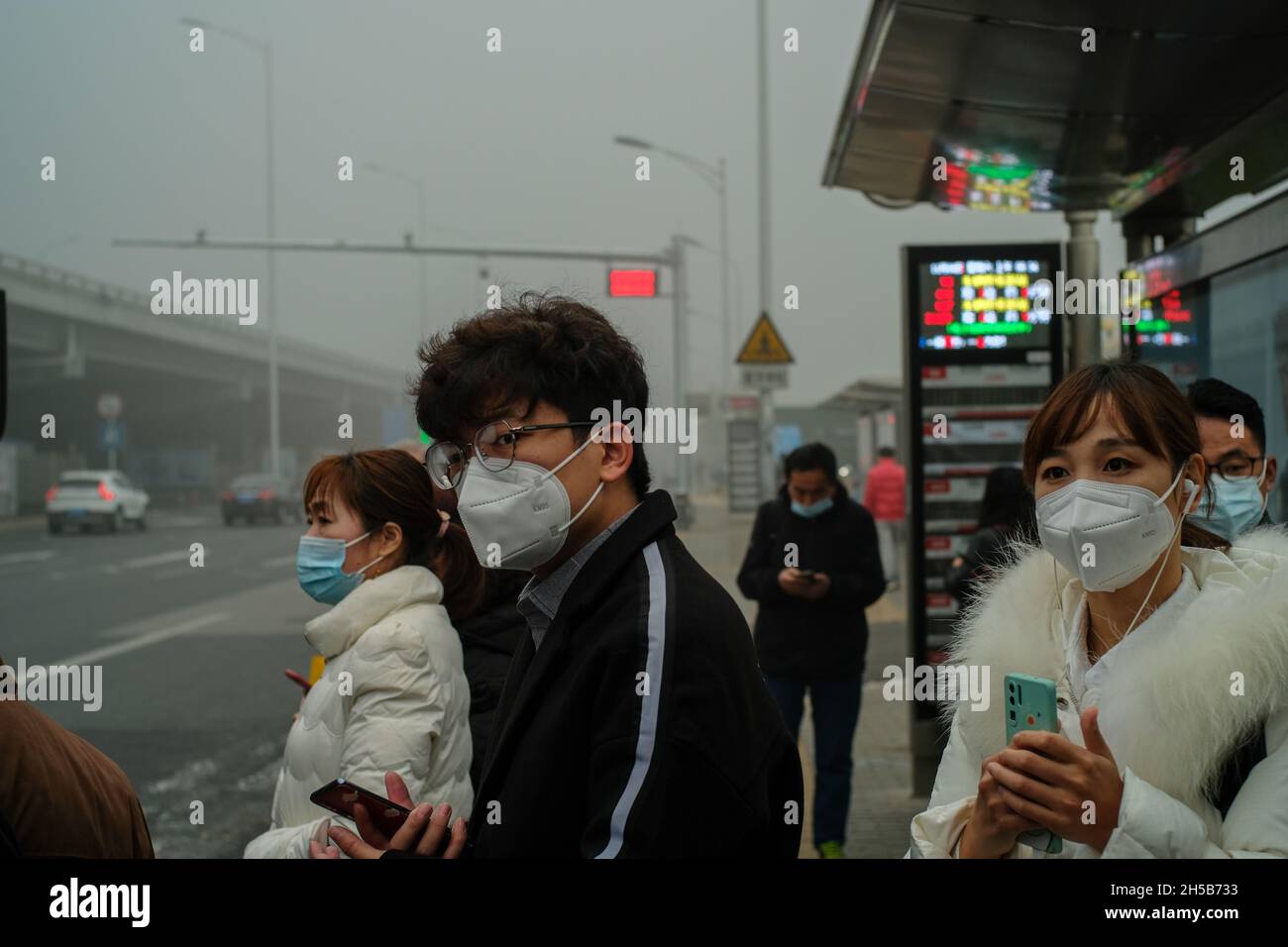 People wear masks to protect against both covid-19 and heavy smog at a bus station in Beijing, China. 06-Nov-2021 Stock Photo