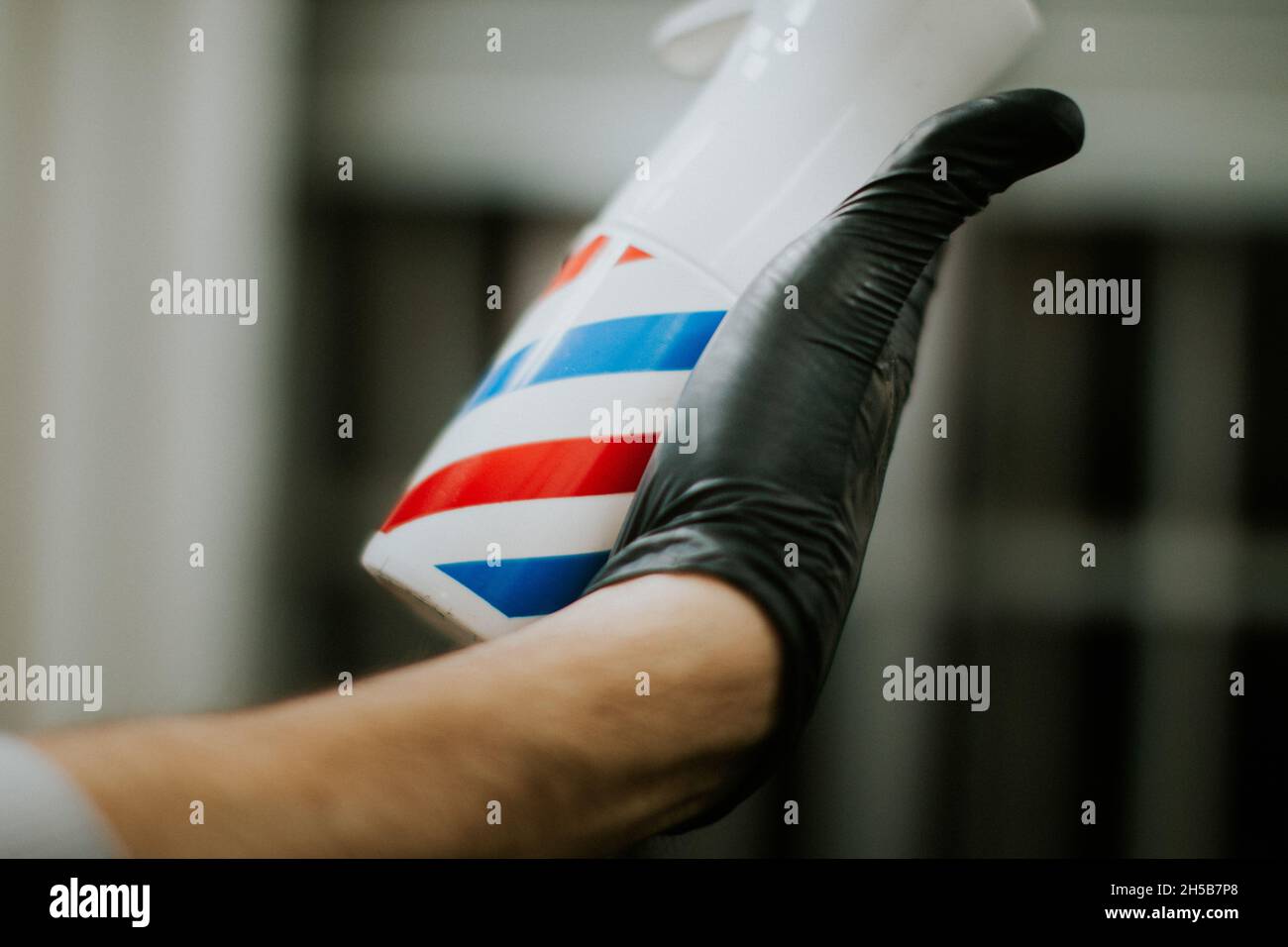 Close up of a Barber spry in a hand with a black glove. hairstyle male