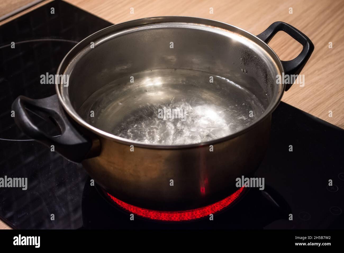 Metal pan with boiling water on the induction cooker red hot plate Stock Photo