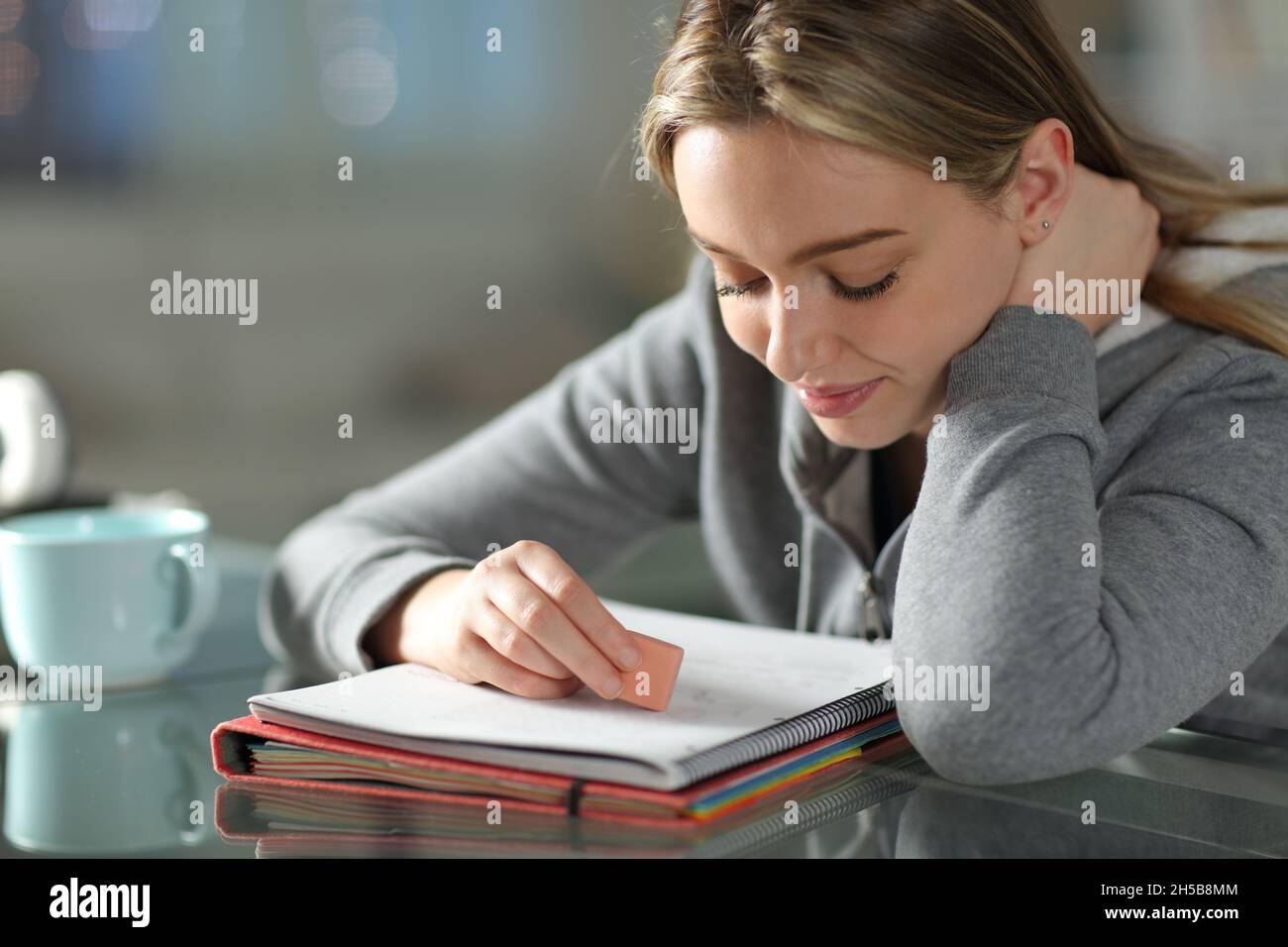 Student erasing text on notebook using eraser at home Stock Photo Alamy