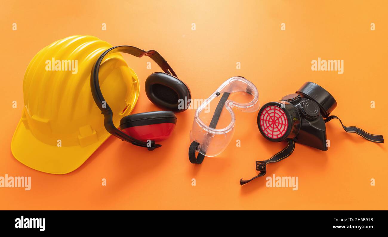 Work wear safety protection equipment on orange color background, personal protective gear. Industrial construction site worker health and safety conc Stock Photo