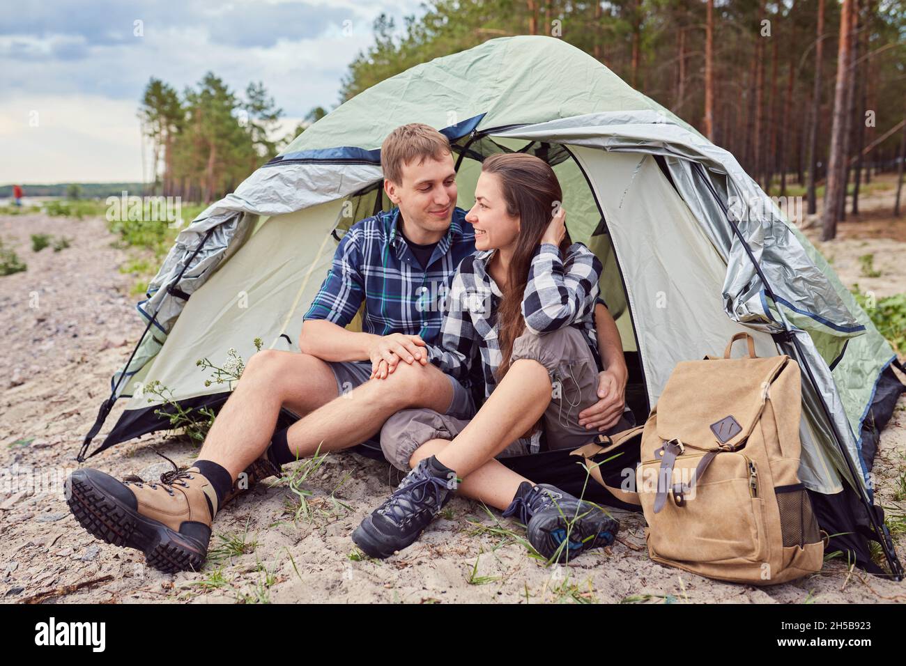 Romantic couple camping outdoors and sitting in a tent. Happy Man and ...