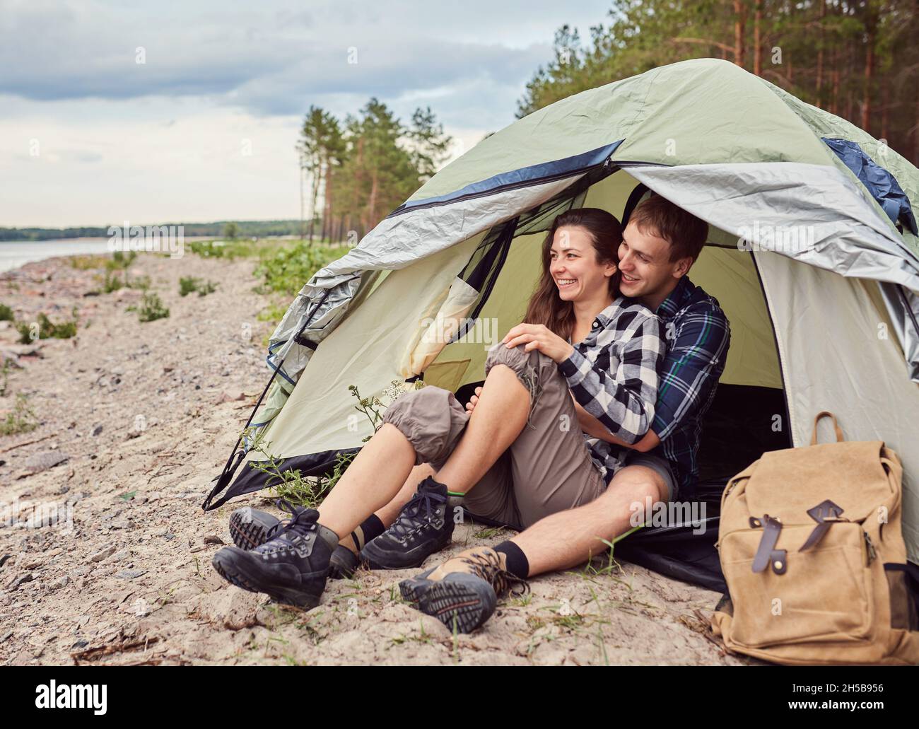 Romantic couple camping outdoors and sitting in a tent. Happy Man and ...