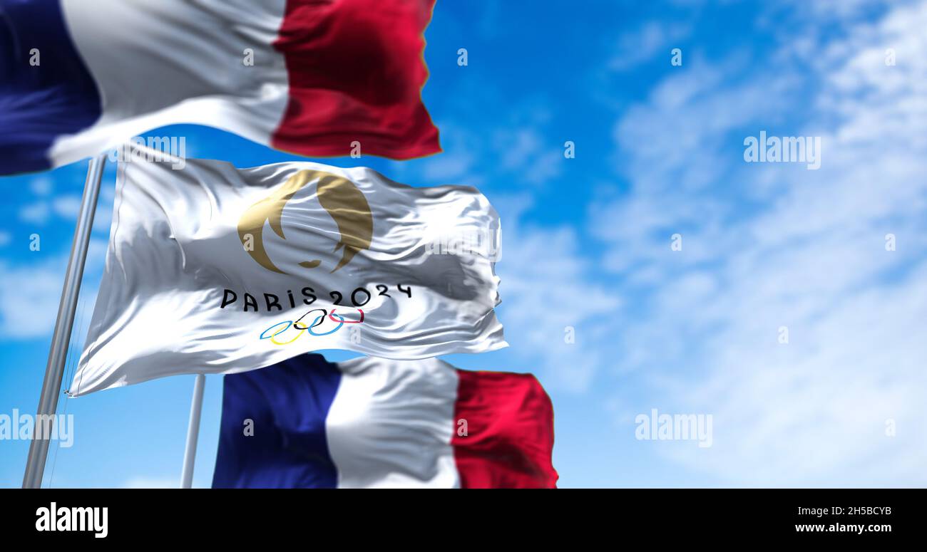 Tokyo, Japan, July 2021: Paris 24 Olympic flag waving in the wind between two French flags. Paris 2024 summer olympics games are scheduled from 26 Jul Stock Photo