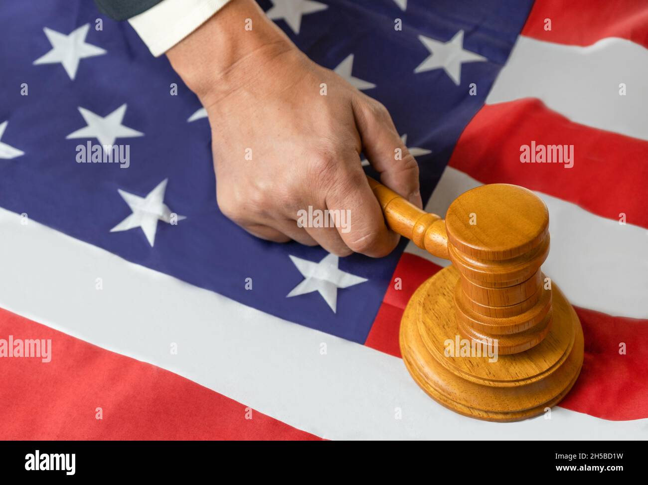 Judge's hand holding wooden gavel to bang on sounding block in the court room on usa united