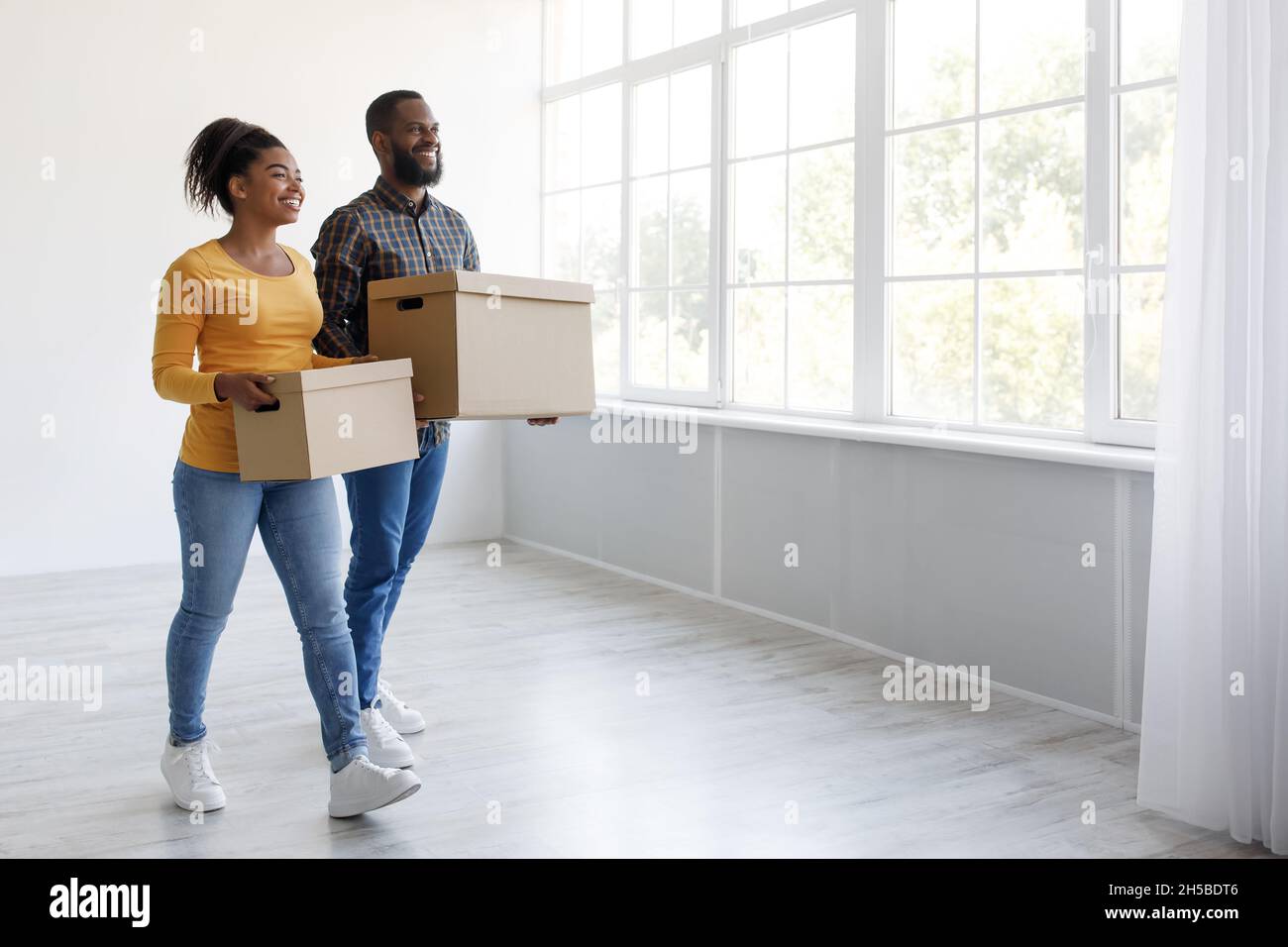 Cheerful glad millennial african american husband and wife carry ...