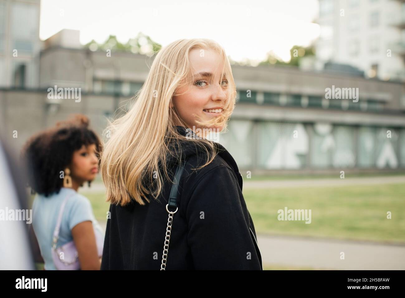 Smiling teenage girl walking with female friend at park Stock Photo