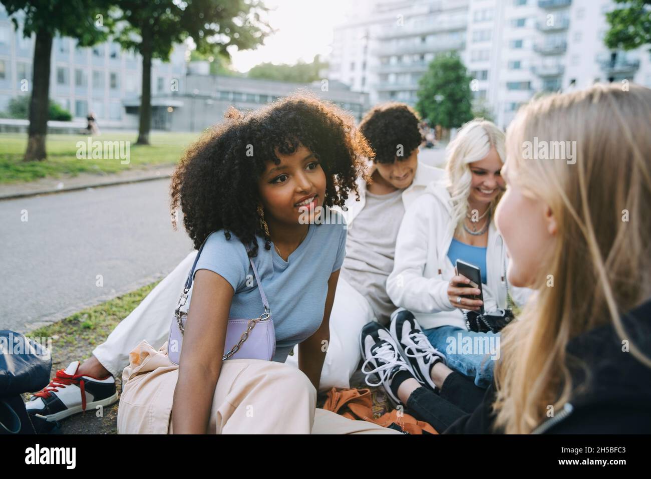 Female and male friends spending leisure time in park Stock Photo