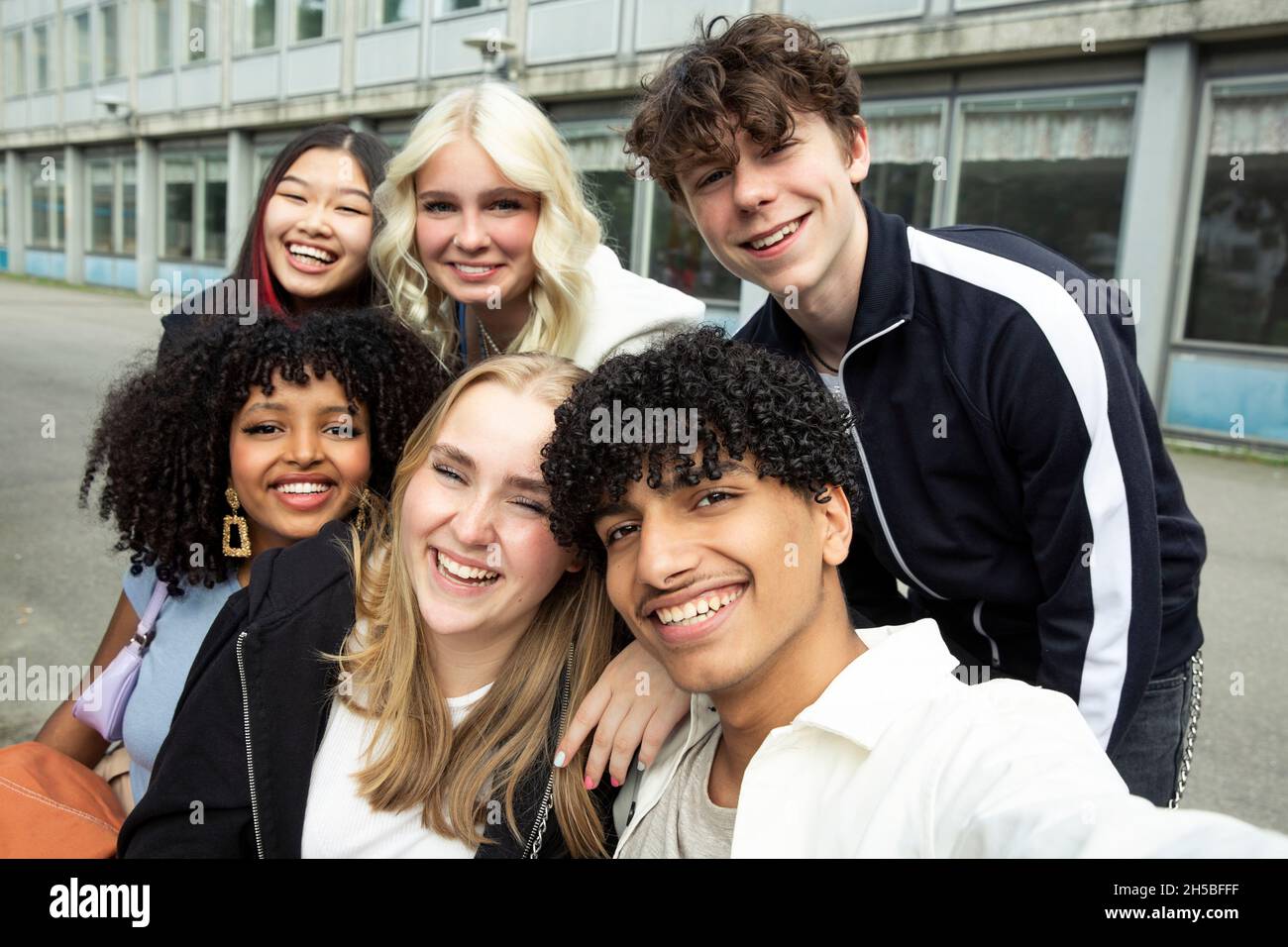 Portrait of smiling male and female friends against building Stock Photo