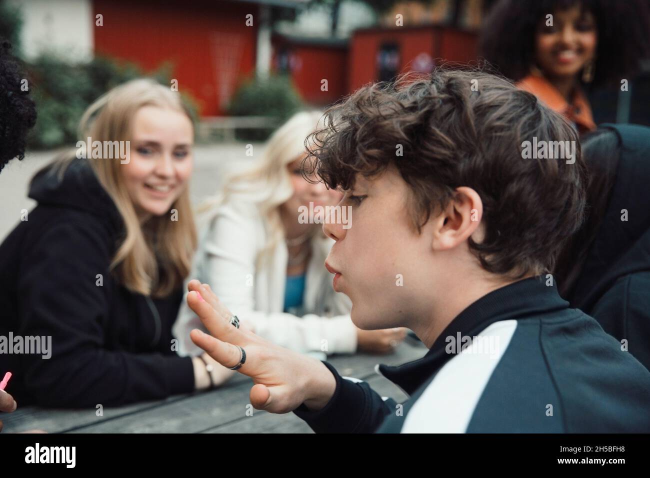 Male teenager blowing nail polish while sitting with friends Stock Photo